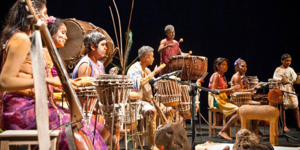 Músicos de carimbó tocando curimbós e maracas em apresentação no palco