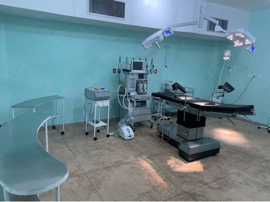 Sala cirúrgica equipada com mesa de cirurgia, focos de luz e aparelho de anestesia