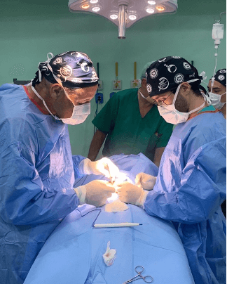 Equipe cirúrgica paramentada realizando um procedimento sob o foco cirúrgico