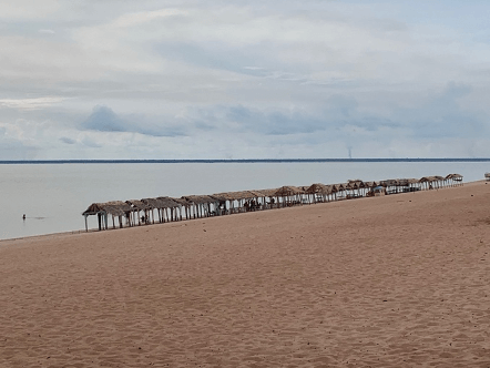 Barracas de palha enfileiradas em praia de areia clara às margens do rio Tapajós