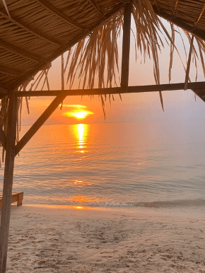 Pôr do sol sobre o rio Tapajós visto de dentro de uma barraca de palha na praia