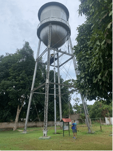 Caixa d'água metálica da era Ford em Belterra, com uma pessoa ao pé da torre