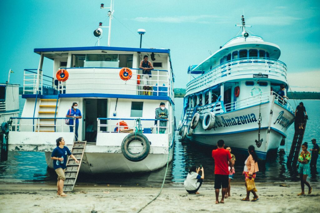 Barco Abaré II atracado na praia de uma comunidade do rio Arapiuns, com voluntárias da ONG Zoé de camiseta azul no convés e moradores na areia